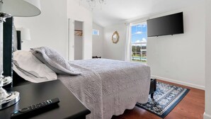Un dormitorio con cama, televisor montado en la pared, candelabro y vista al exterior.