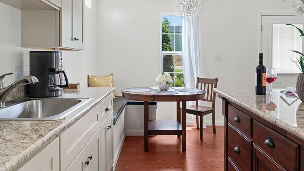 Una cocina moderna con cafetera, una mesa de comedor con sillas y vistas al exterior a través de una ventana.