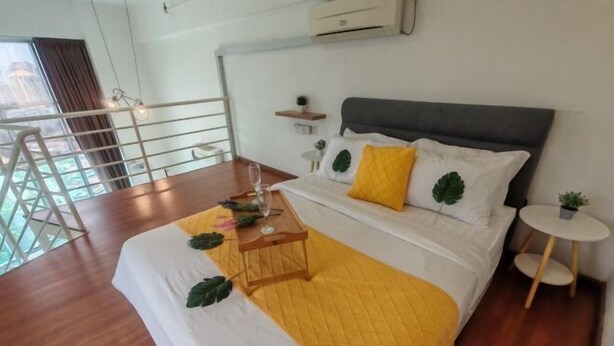 A hotel room with a bed, a small table, a chair, a balcony, and a view of the city. - The CEO By SY Staycation (Bayan Lepas)