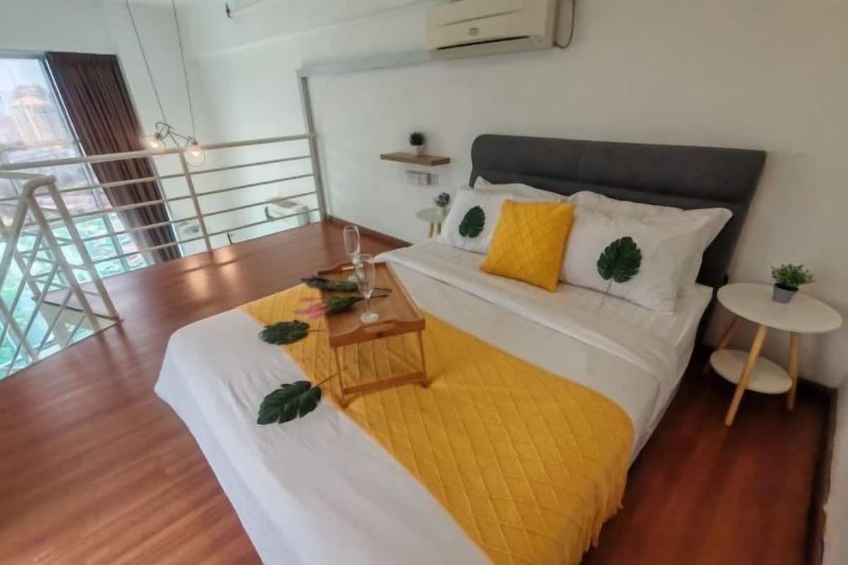 A hotel room with a bed, a small table, a chair, a balcony, and a view of the city.