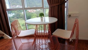 A room with a round table and four chairs, a potted plant on the table, and a view of a mountainous landscape through large windows. - The CEO By SY Staycation (Bayan Lepas)