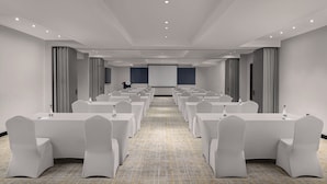 A conference room with rows of white tables and chairs, a projector screen, and a tiled floor. - Four Points® by Sheraton Accra Airport Hotel (Accra)