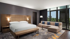 A modern hotel room with a large bed, a sofa, a bench, a nightstand, and a lamp. - Four Points® by Sheraton Accra Airport Hotel (Accra)