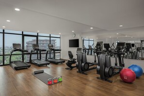Ein Fitnessstudio mit Laufbändern, Crosstrainern und Kurzhanteln.