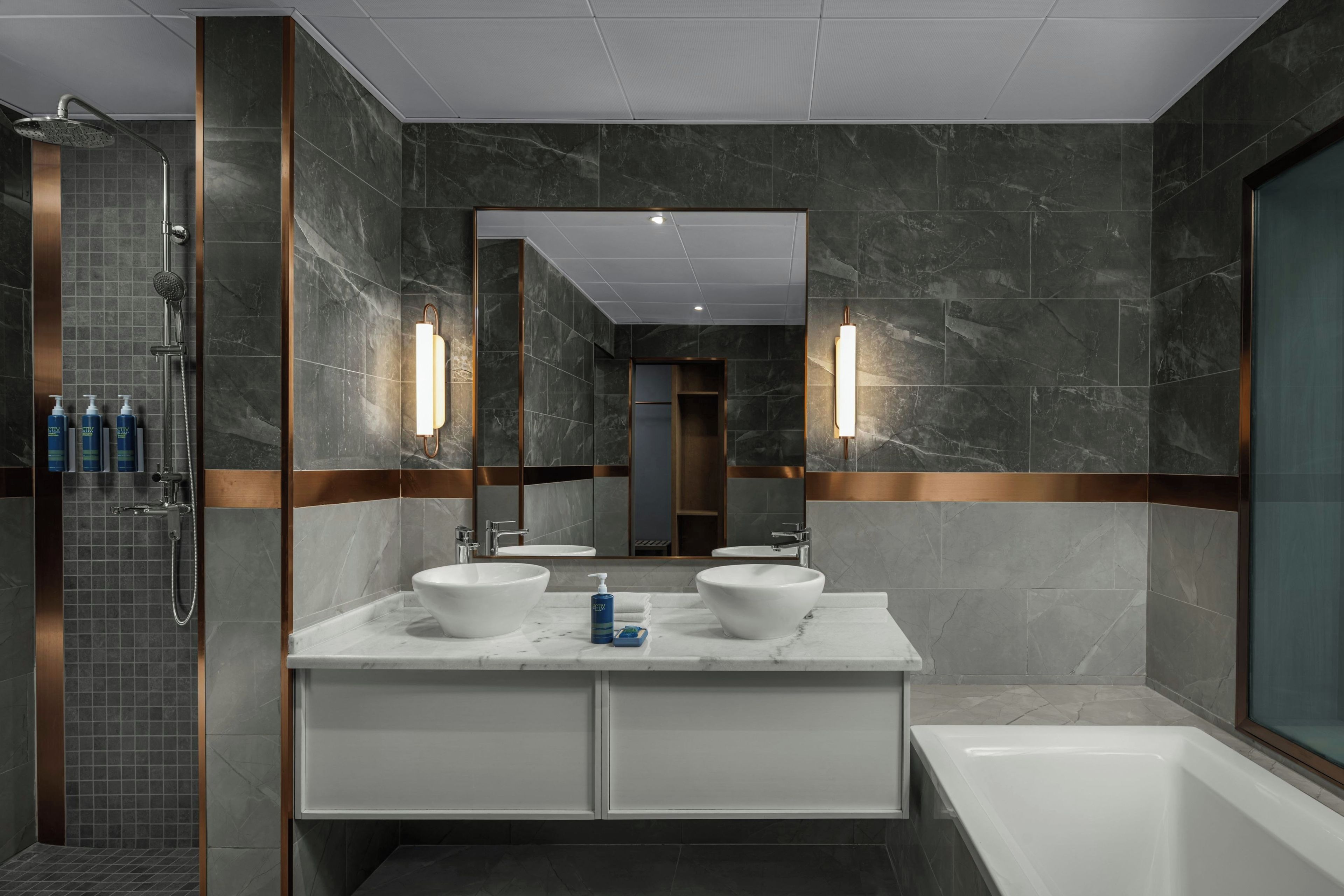 A modern bathroom with a walk-in shower, two sinks, and a large mirror.