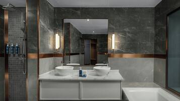 A modern bathroom with a walk-in shower, two sinks, and a large mirror.