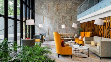 A modern lobby with seating, plants, and a stone wall.