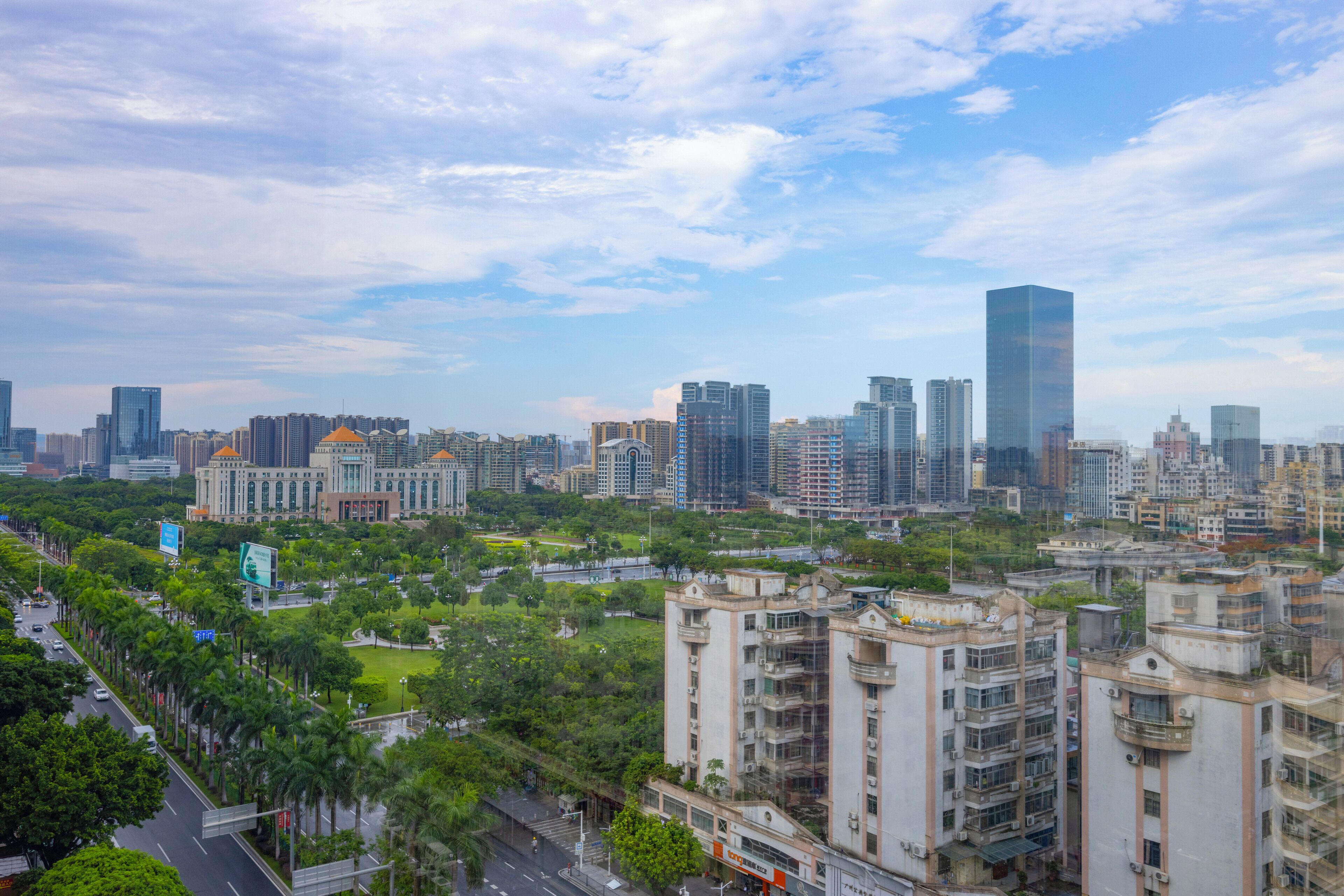 A cityscape with high-rise buildings, a mix of modern and traditional architecture, and a green park area.