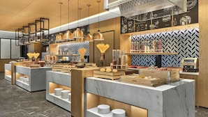 Una barra de desayuno moderna con encimeras de mármol y detalles de madera, que presenta diferentes alimentos y elementos decorativos.
