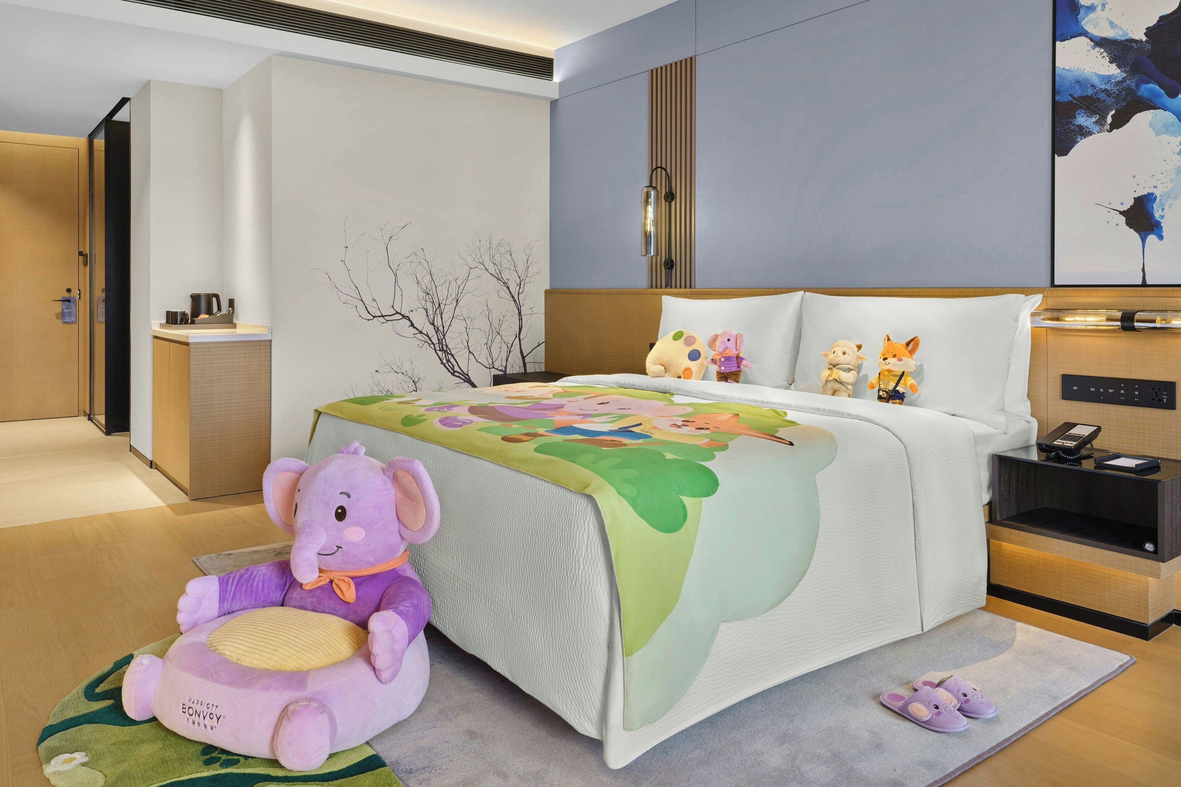 A hotel room with a bed, a nightstand, a plush toy, and a small cabinet.