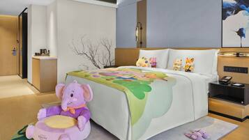 A hotel room with a bed, a nightstand, a plush toy, and a small cabinet.