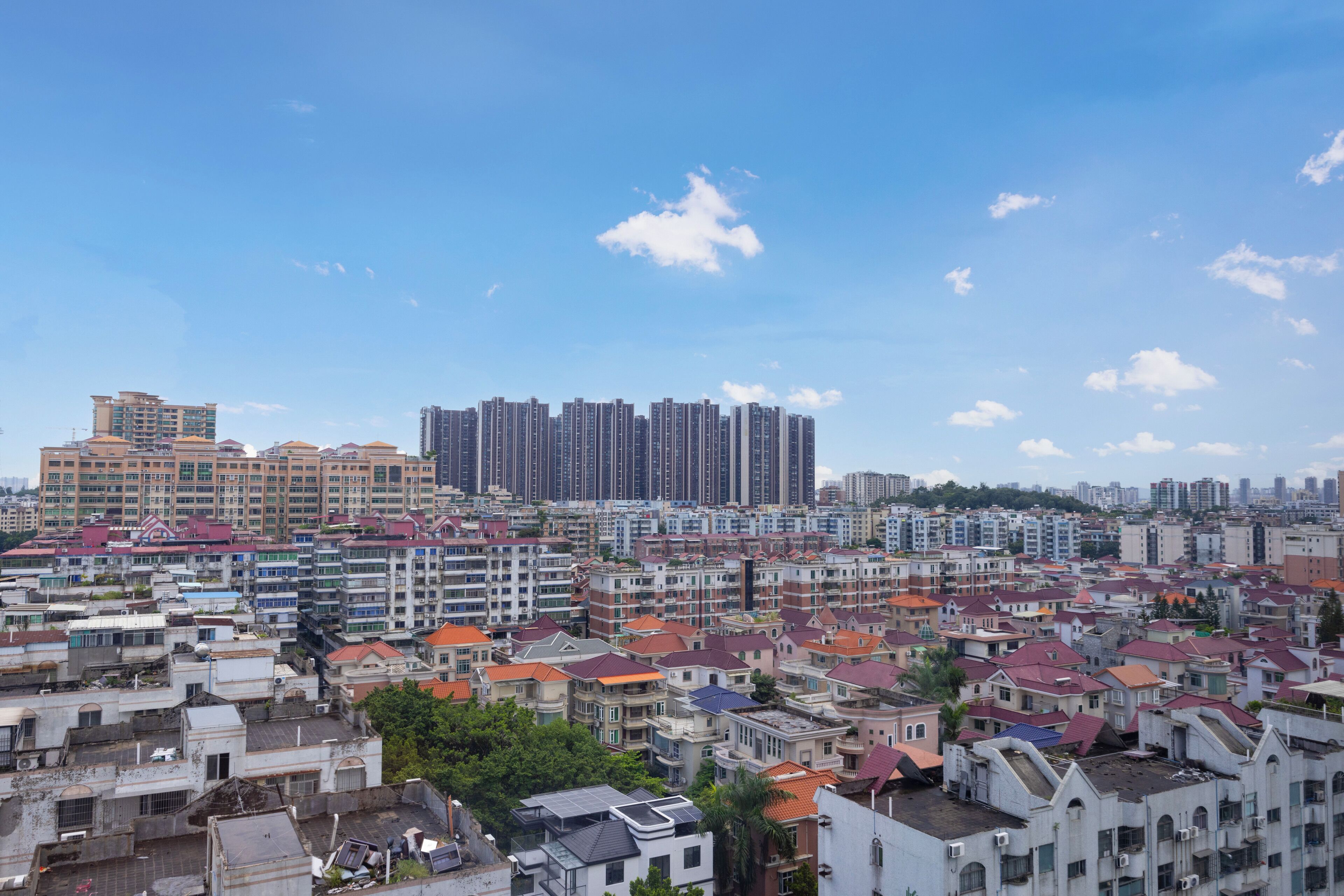 Uma área residencial urbana densa, com diversos estilos arquitetônicos e um céu azul límpido.