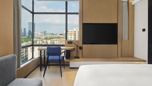 A modern hotel room with a large window, a bed, a desk, and a chair. - Fairfield By Marriott Guangzhou Huadu (Guangzhou)
