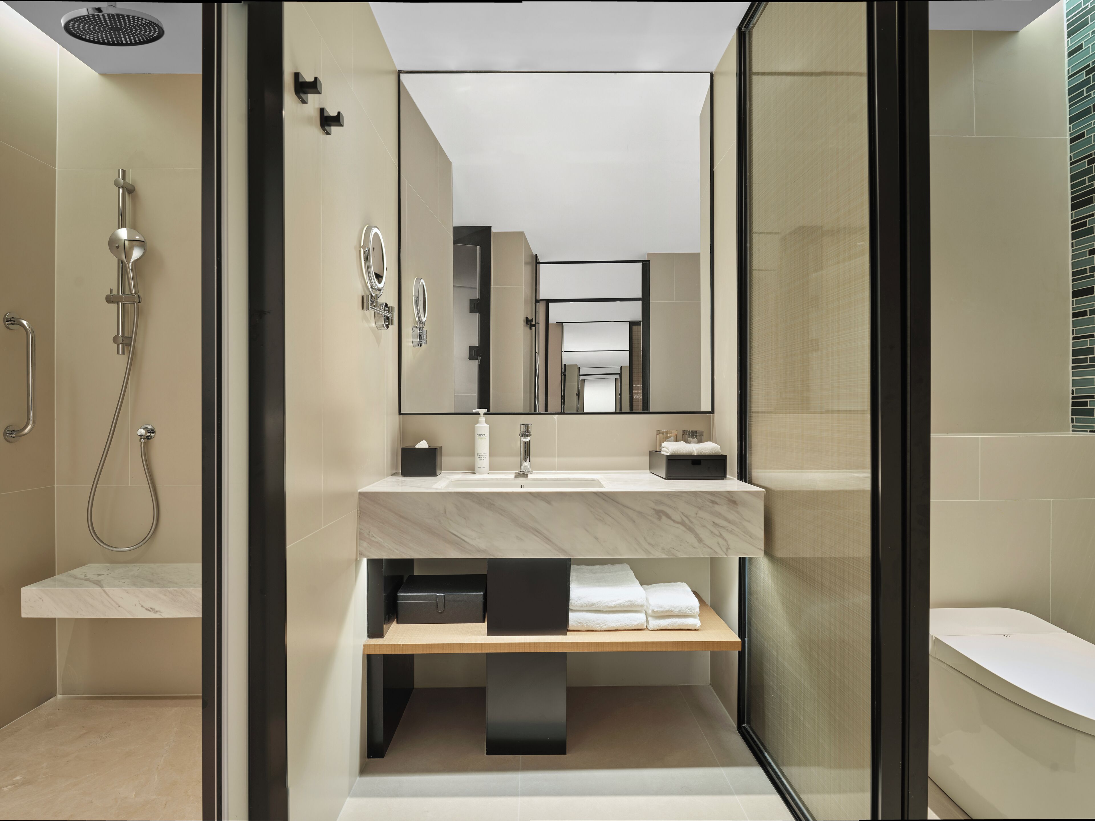 A modern bathroom with a glass-enclosed shower, a vanity with a mirror, and a towel rack.
