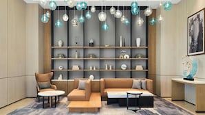 Una sala moderna con un sofá modular, sillones y una mesa de centro. Se observan estanterías con objetos decorativos y un cuadro en la pared.