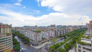 A cityscape with multi-story residential buildings, a wide road, and a clear sky.