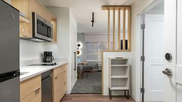 Una cocina compacta con electrodomésticos modernos, un comedor con una pequeña mesa y sillas, y una unidad de almacenamiento empotrada.