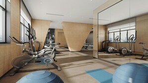 A modern gym with cardio machines, exercise balls, and a large window providing natural light.