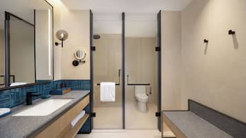 A modern bathroom with a glass-enclosed shower, a large mirror, and a dual sink vanity.