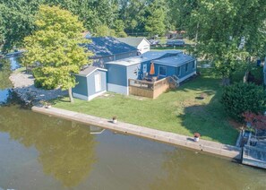 A lakeside property with a dock, a small shed, and a house with a deck.