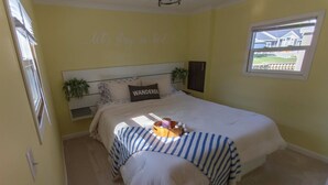 A bedroom with a bed, a bedside table, a window, and a wall with a sign. - Cozy 1-bedroom mobile home on the beautiful Crooked lake (Angola)