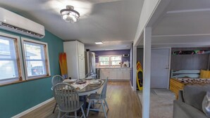 A modern kitchen with white cabinets, a dining table with chairs, and a visible microwave. - Cozy 1-bedroom mobile home on the beautiful Crooked lake (Angola)
