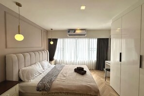 Una habitación de hotel moderna con una cama grande, un escritorio y un armario.