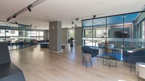 A modern interior with a mix of seating areas, glass partitions, and a visible outdoor balcony.