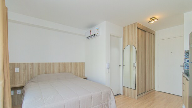 A bedroom with a bed, a wardrobe, and a mirror.