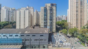A high-rise residential building with multiple floors, a parking lot, and a street with cars.