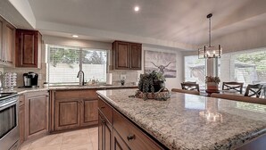 A spacious kitchen with granite countertops, wooden cabinets, and a central island. - Fabulous 4-bedroom house with pool in Scottsdale (Scottsdale)