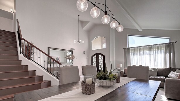 A spacious living room with a wooden staircase, a large dining table, and a modern chandelier. - Fabulous 4-bedroom house with pool in Scottsdale (Scottsdale)