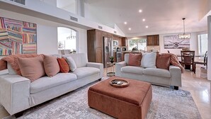 A spacious living room with two sofas, a coffee table, and a kitchen in the background. - Fabulous 4-bedroom house with pool in Scottsdale (Scottsdale)