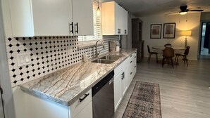 Una cocina moderna con armarios blancos, encimera de mármol y salpicadero decorado.