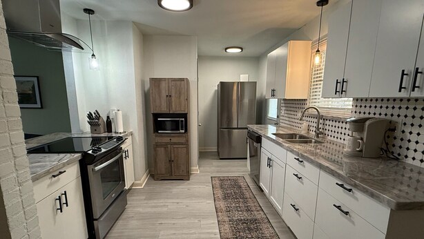 Una cocina moderna con electrodomésticos integrados, una isla central y un salpicadero con diseño.