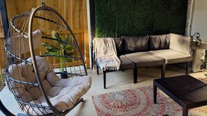 Un espacio al aire libre acogedor con una silla colgante, un sofá y una mesita de centro.