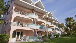Un hôtel à plusieurs étages doté de balcons, d’un espace piscine et d’une végétation luxuriante.