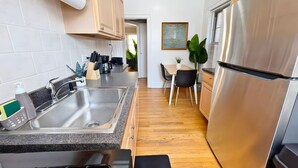 A modern kitchen with stainless steel appliances, a granite countertop, wooden cabinets, and a dining area with a table and chairs. - Perfectly Located 1BR - Hinman D2 (Evanston)