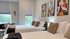 Une chambre d’hôtel avec deux lits, un bureau et des œuvres d’art accrochées au mur.