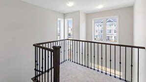 A spacious balcony with a wooden railing and a view of neighboring buildings.