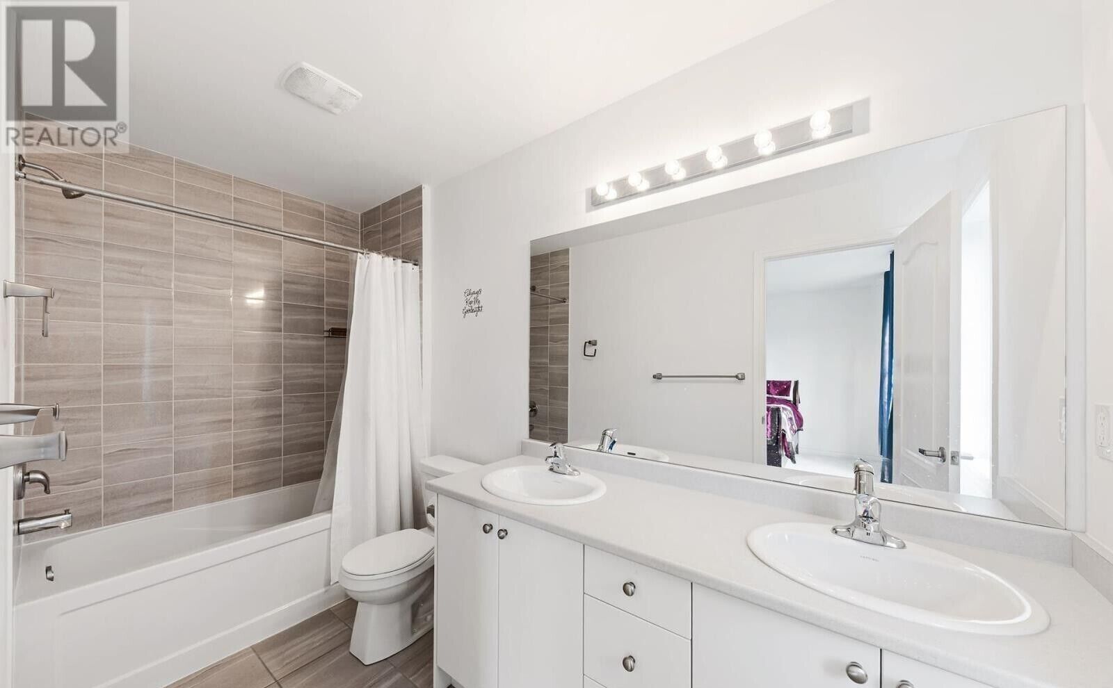 Un baño moderno con dos lavamanos, ducha e inodoro.