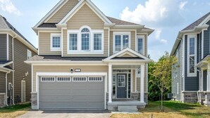 A two-story residential house with a central garage, a front porch, and a symmetrical facade.