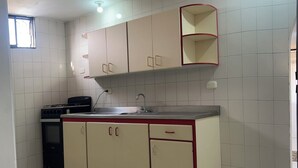 A kitchen with white tiled walls, a built-in oven, a sink, and cabinets with red handles. - Balconee Big Apartment Centre (Santa Marta)