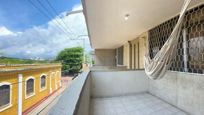 A balcony with a view of a yellow building, a hammock, and a metal gate. - Balconee Big Apartment Centre (Santa Marta)