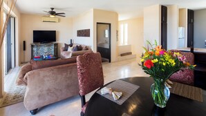 A living room with a sofa, chairs, a coffee table, a TV, and a vase with flowers.
