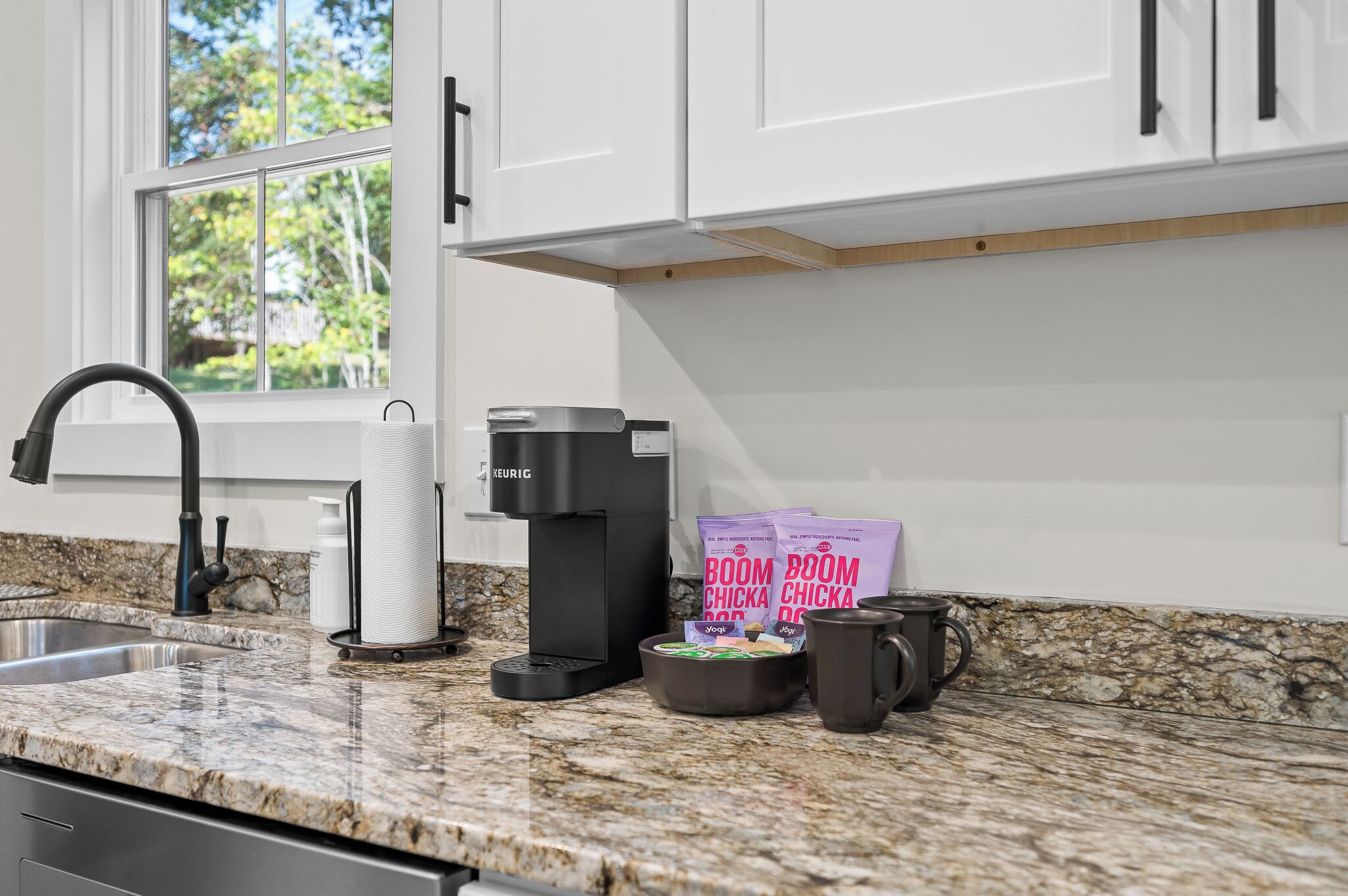 A modern kitchen with a built-in coffee maker, a kettle, and coffee pods on the counter.