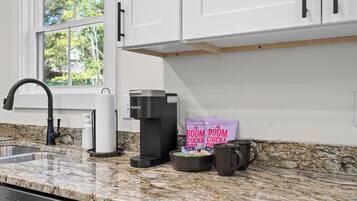A modern kitchen with a built-in coffee maker, a kettle, and coffee pods on the counter.