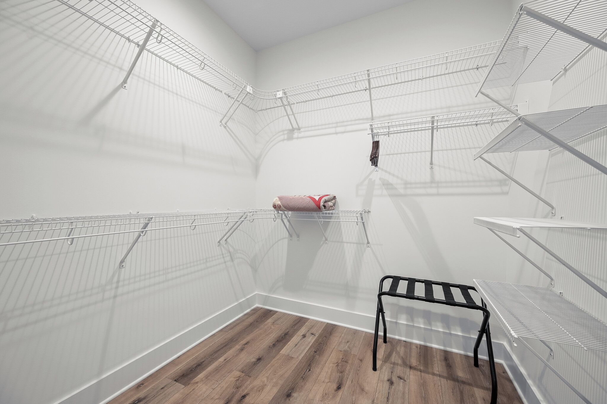 Una habitación con suelo de madera, paredes blancas y estanterías metálicas.