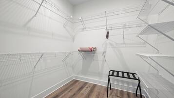 Una habitación con suelo de madera, paredes blancas y estanterías metálicas.
