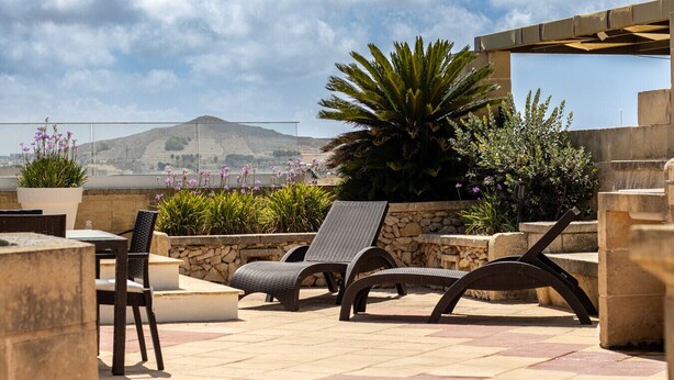 An outdoor patio with wicker chairs, a table, and potted plants. - ROOFTOP HIDEAWAY, JACUZZI, BBQ & PETss (L-Għarb)